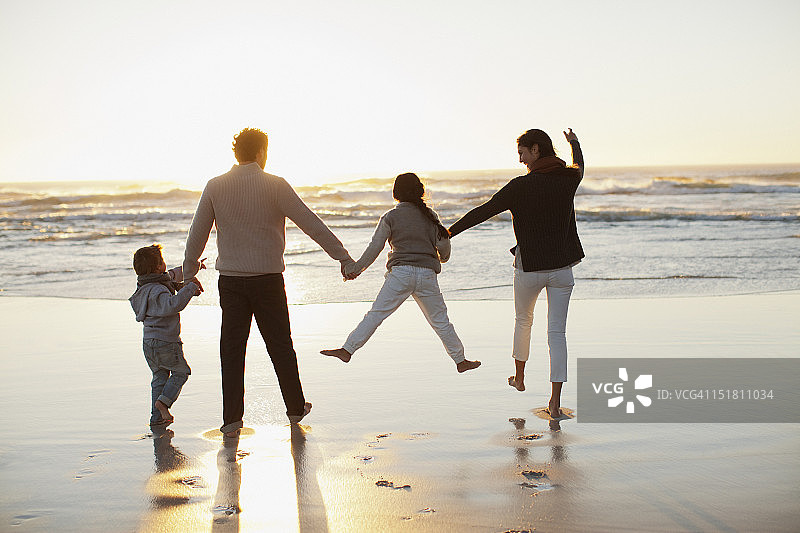 日落时分，一家人在海滩上牵着手图片素材
