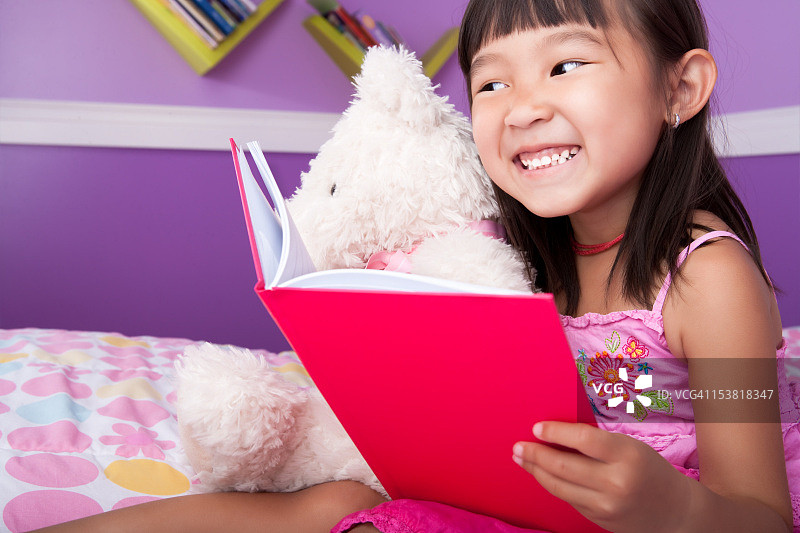 可爱的亚洲女孩在卧室阅读图片素材