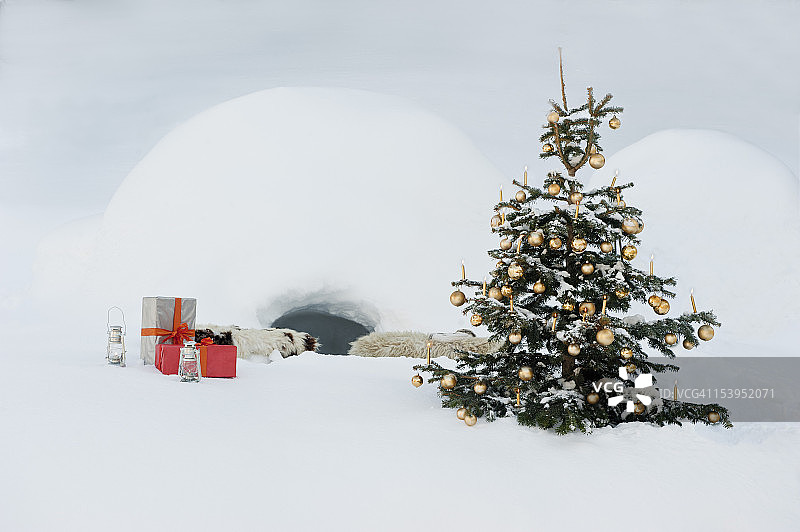 奥地利萨尔茨堡县，圣诞树和礼物都放在雪中的冰屋前图片素材
