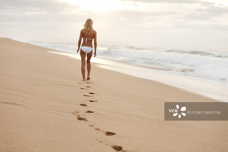 迷人的年轻女子在白色比基尼走在夏威夷海滩上图片素材