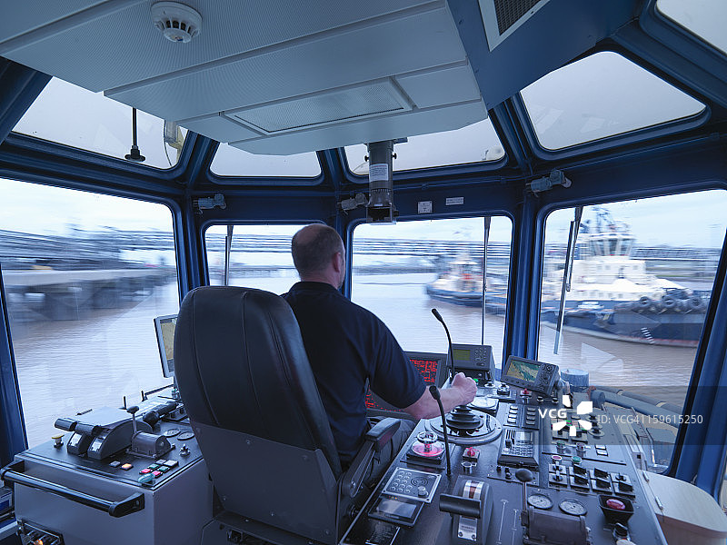 船长驾驶拖船出海，可以看到船桥和窗外的景色图片素材