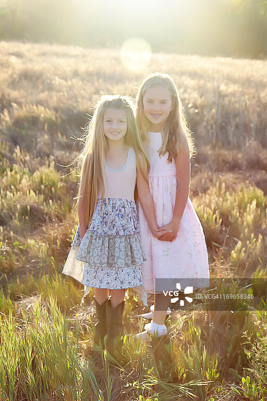 姐妹们手牵着手站在阳光明媚的田野里图片素材