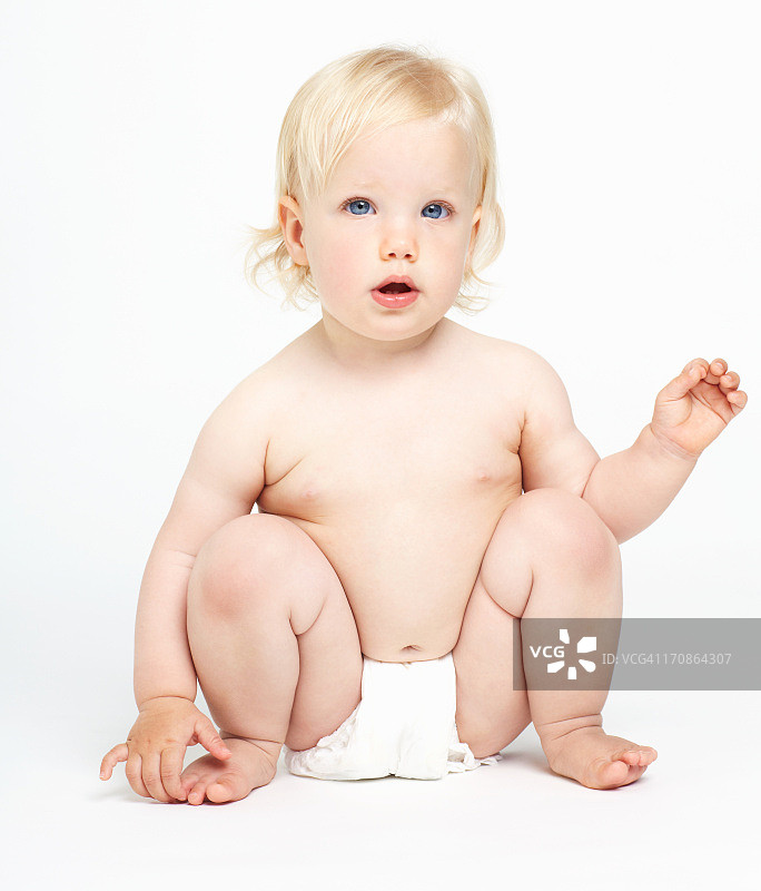穿着尿布的婴儿坐在白色的背景上图片素材