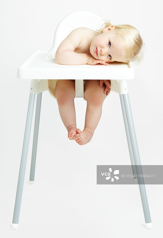 婴儿坐在高椅子上，白色背景图片素材