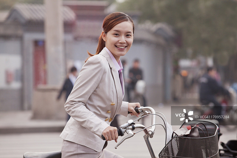 年轻的女商人站着一辆自行车，北京，中国图片素材