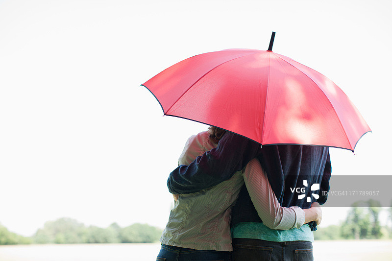 情侣在红伞下拥抱图片素材