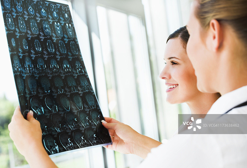 两名年轻女性在医疗保健部门检查大脑的核磁共振影像图片素材