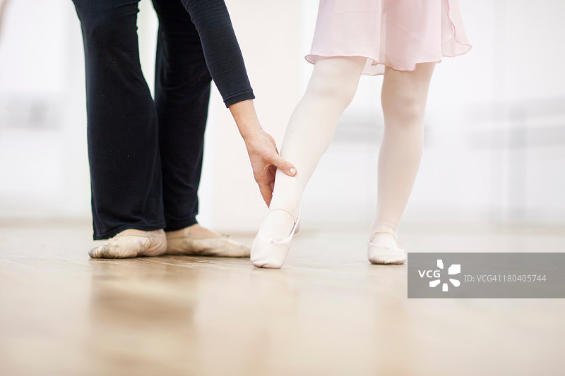 一个年轻的芭蕾舞演员和老师练习脚趾点图片素材