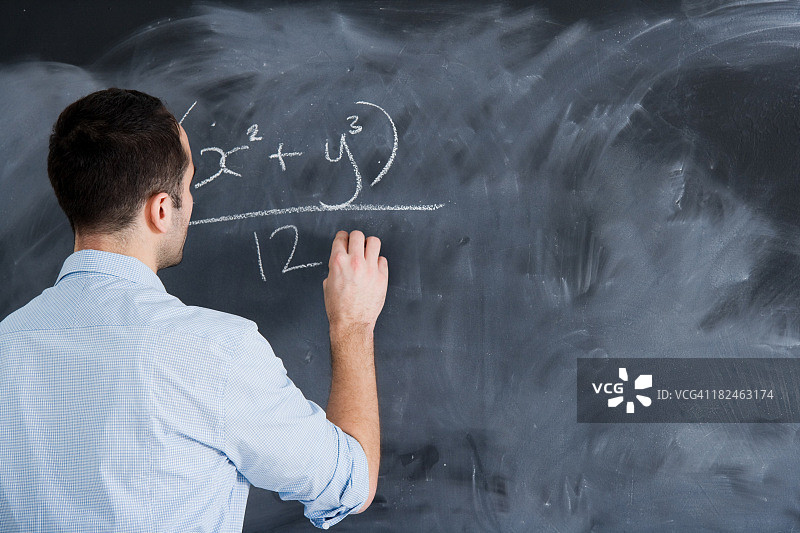 男老师在黑板上写一个代数方程图片素材