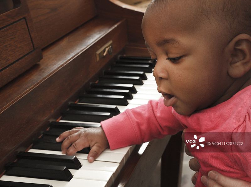 母亲，收养的非洲混血女儿在弹钢琴图片素材