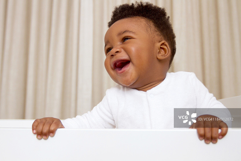 快乐的非洲男婴站在南非开普敦的婴儿床上图片素材