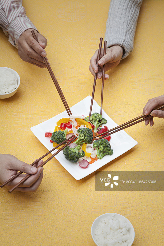 近距离的人拿着筷子和分享一个盘子图片素材