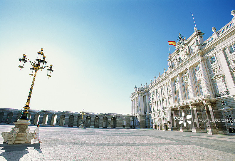 西班牙，马德里，一个女人靠在王宫对面的灯柱上图片素材