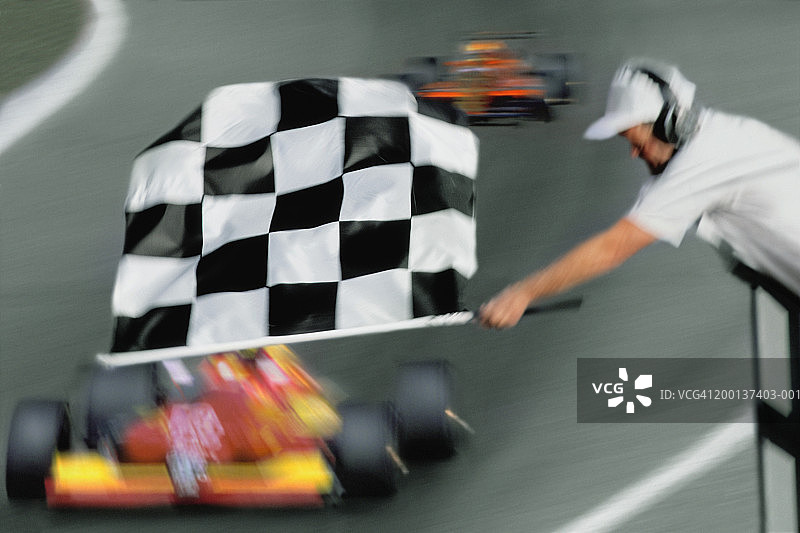 比赛官员在赛车上方挥舞方格旗(模糊动作)图片素材