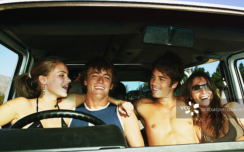 两对年轻夫妇坐在SUV里，笑着图片素材
