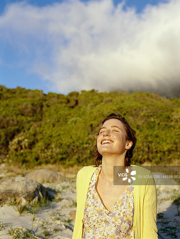 年轻女子在海滩上放松，笑着图片素材