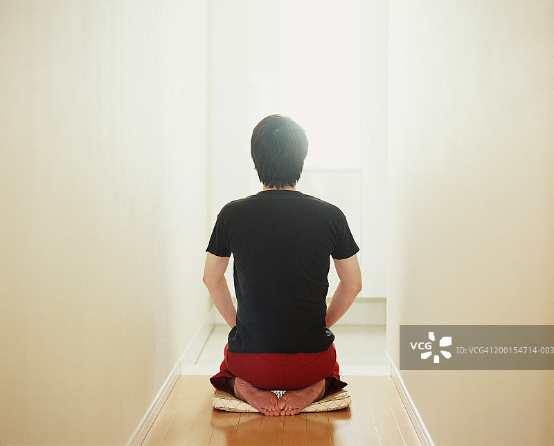 一个男人跪在走廊的垫子上，后视镜图片素材