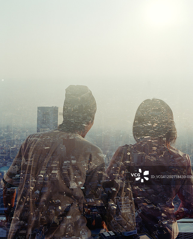 一对情侣在窗口俯瞰城市景观，后视图(多次曝光)图片素材