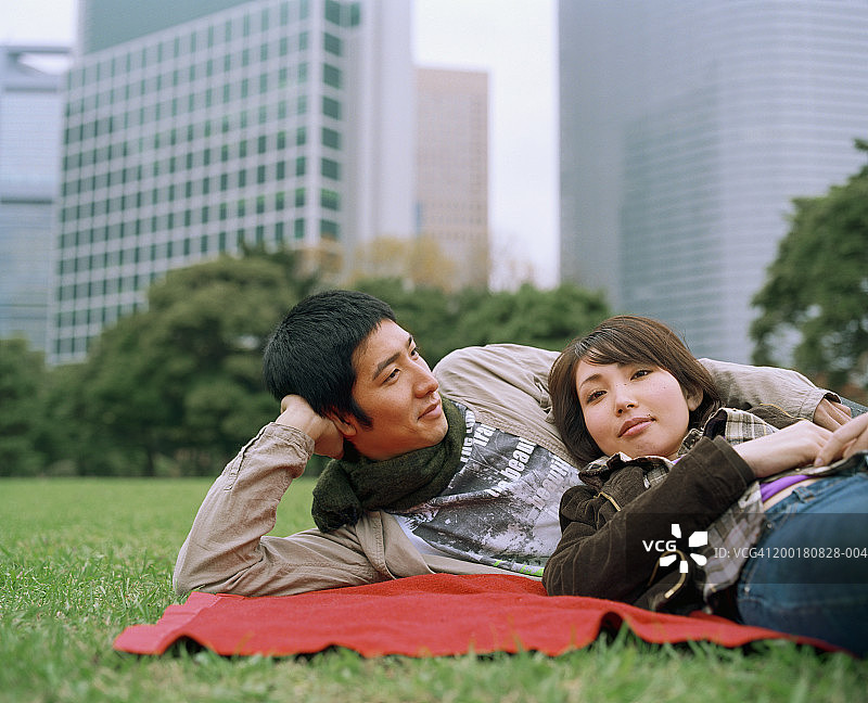 年轻夫妇躺在草地上，画像中的女子图片素材