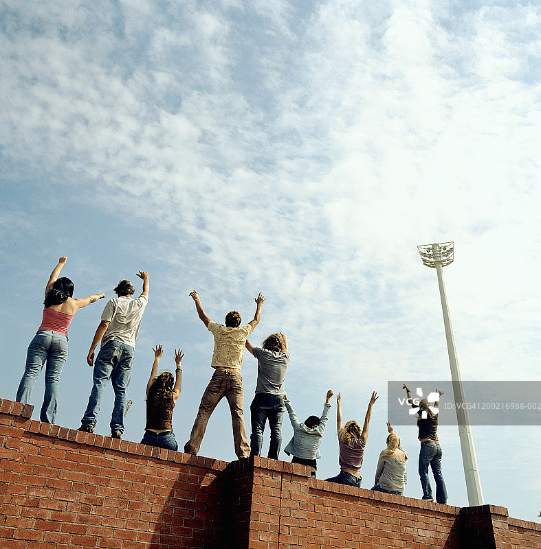 一群年轻人在砖墙上欢腾，后视镜图片素材