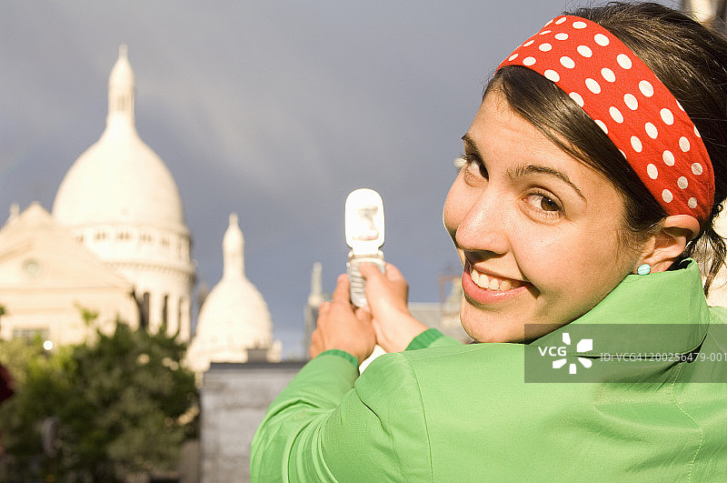 法国，巴黎，一名年轻女子用照相手机拍摄圣心大教堂图片素材