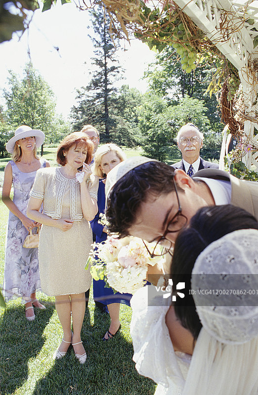 新娘和新郎在花园举行的婚礼上接吻图片素材