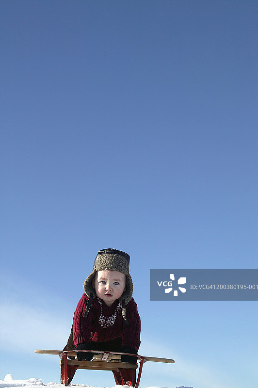 男婴(9-12个月)在雪山上滑雪，低角度观看图片素材