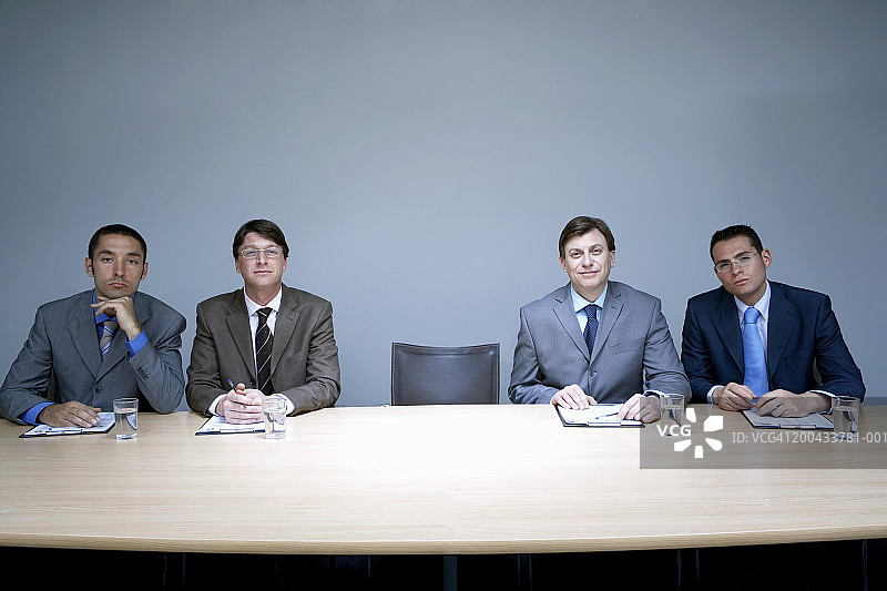 四名商人坐在会议室的空椅子旁，肖像图片素材