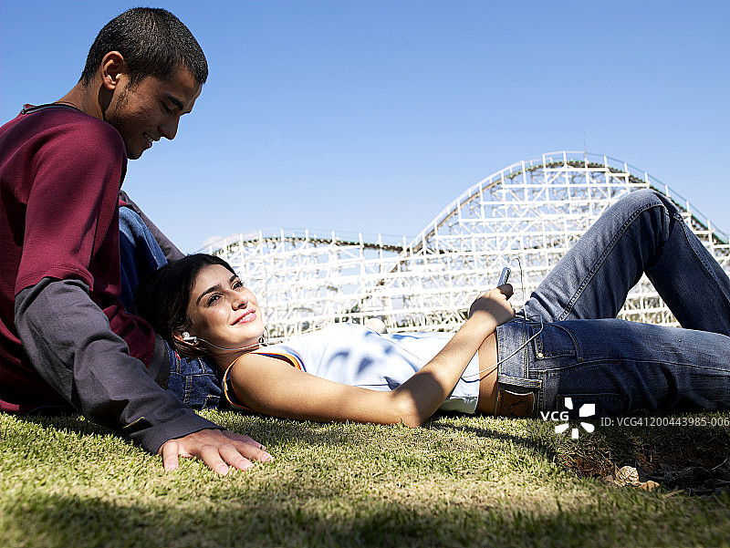 一对年轻夫妇在游乐场的草坪上休息图片素材