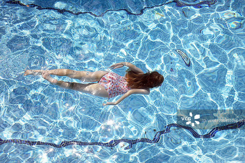 女孩(8-10)在游泳池水下游泳，俯视图图片素材