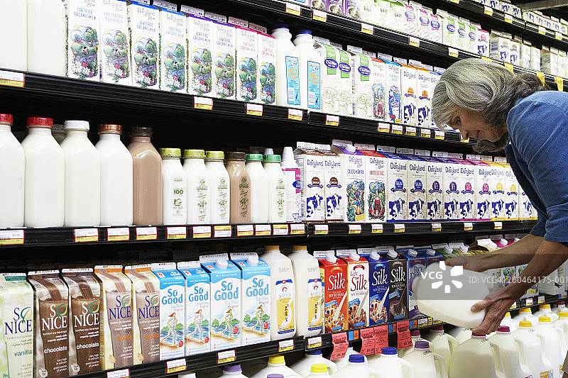 成熟的女人在超市阅读牛奶标签，侧视图，特写图片素材
