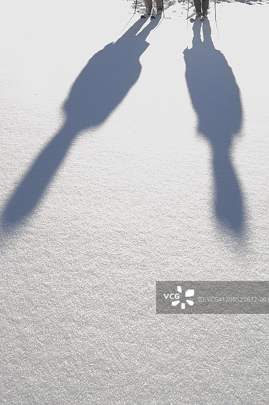 两个滑雪者的影子投射在白雪覆盖的地面，低的部分图片素材