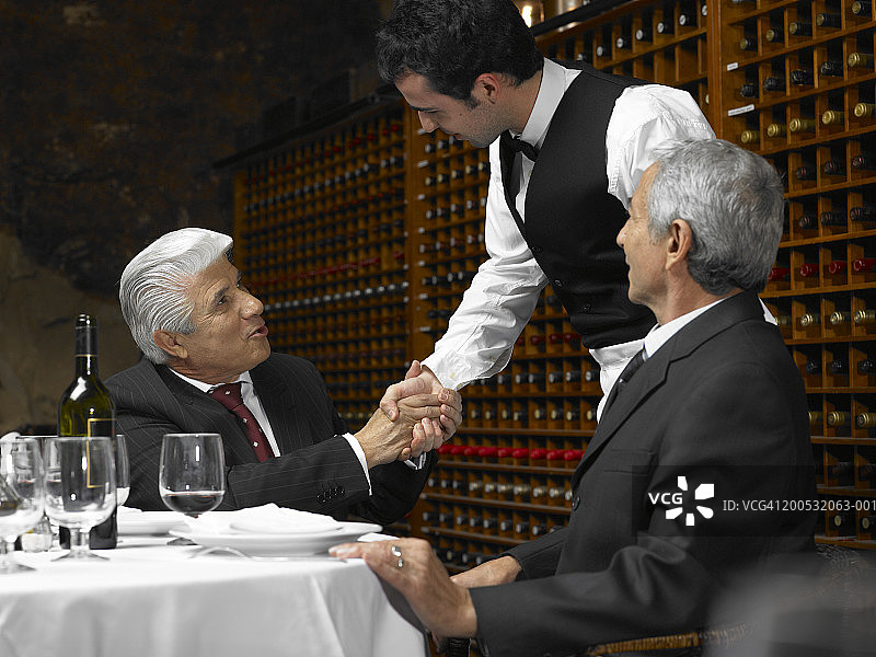 餐厅服务员与资深商人握手图片素材