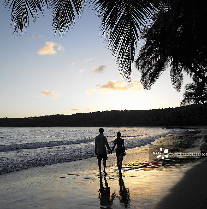 日落时分，一对情侣在海滩上散步图片素材