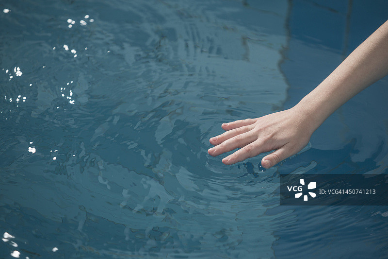 一个小女孩的手使游泳池的水泛起涟漪图片素材