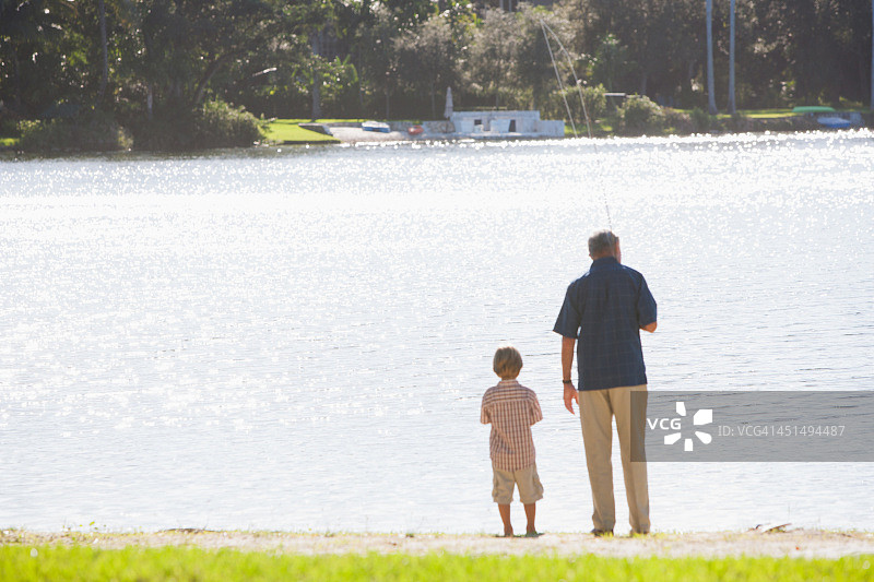 一个男人和一个小男孩在公园外面的一个湖里钓鱼图片素材