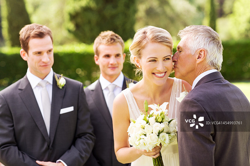 在户外婚礼上，父亲亲吻新娘的脸颊图片素材