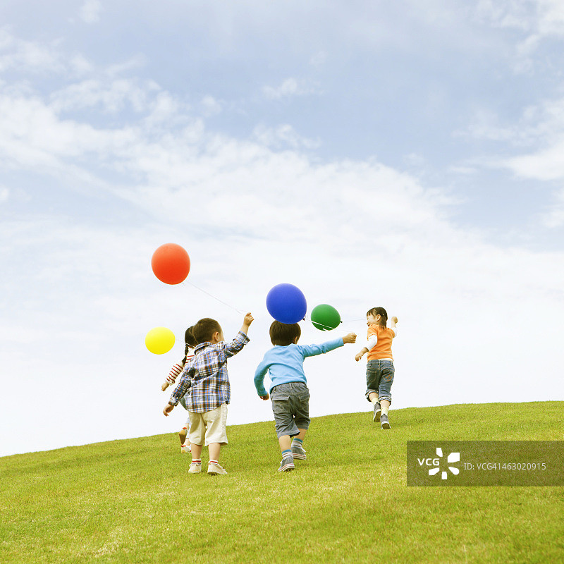 孩子们拿着气球在草地上奔跑图片素材