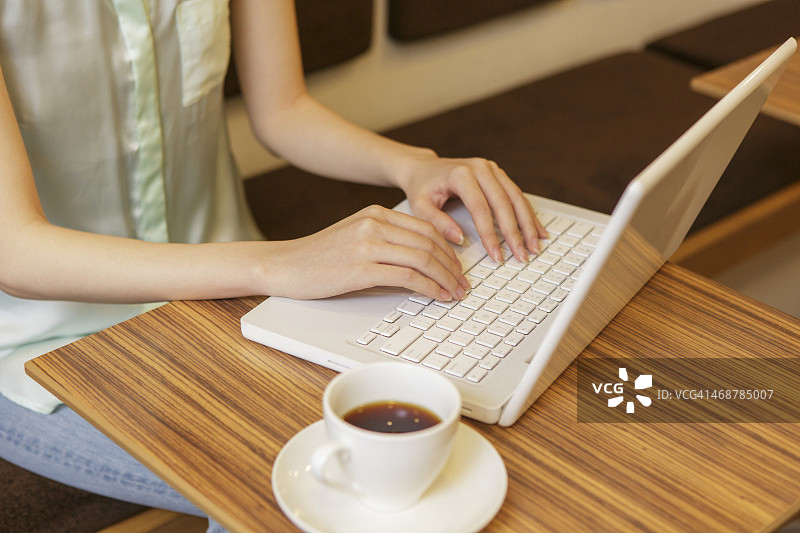 一个年轻女子在咖啡厅用笔记本电脑图片素材