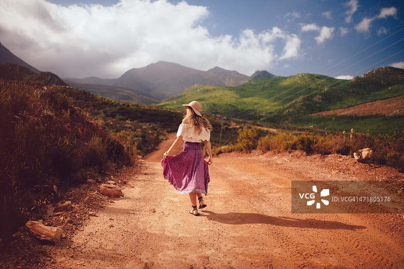 波西米亚女孩走在乡间土路的背影图片素材