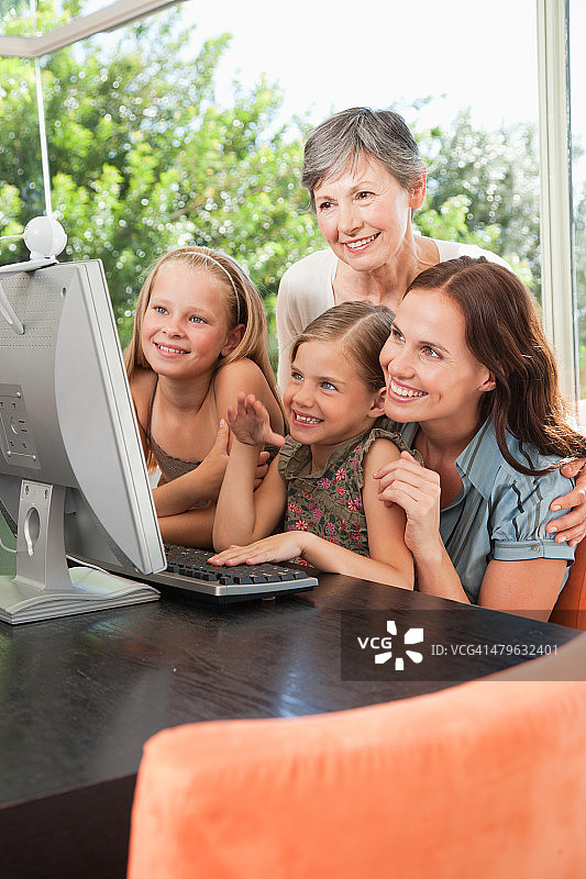 一位母亲和祖母与她的两个孩子一起使用电脑图片素材