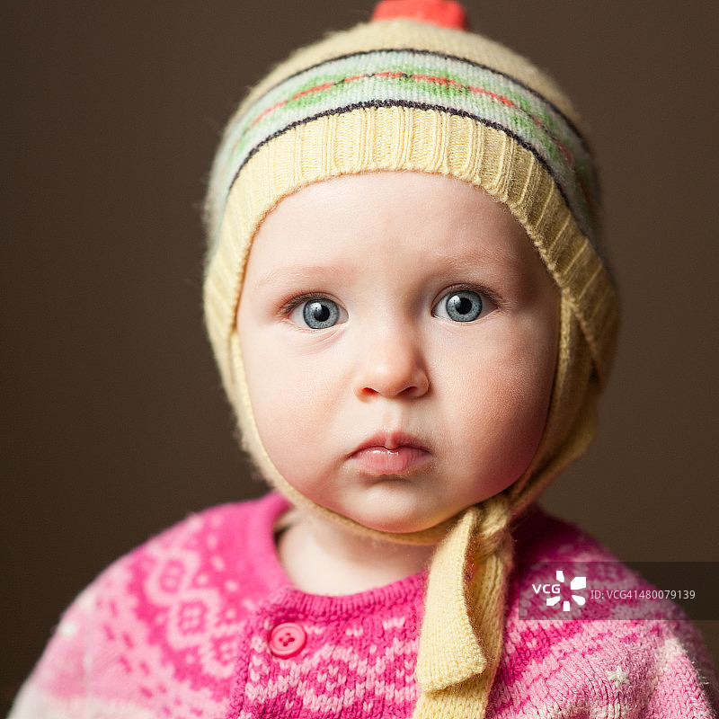 带着羊毛帽子和毛衣的严肃女婴图片素材