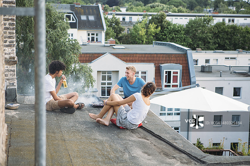 简单的生活:年轻人坐在一起，在屋顶上烧烤图片素材
