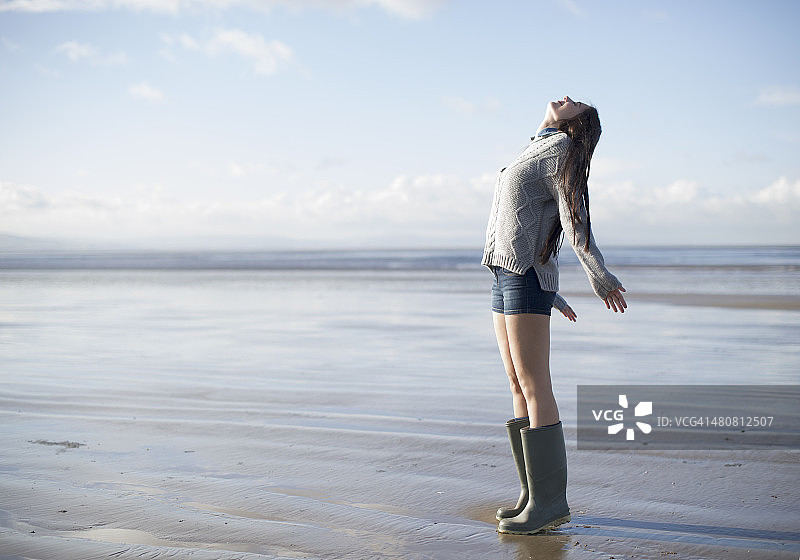 年轻女子站在海滩上向上看，布里恩桑兹，萨默塞特，英国图片素材