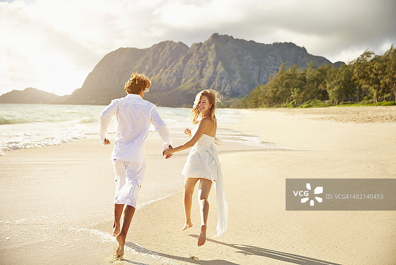 一对在沙滩上跑步的白人夫妇图片素材