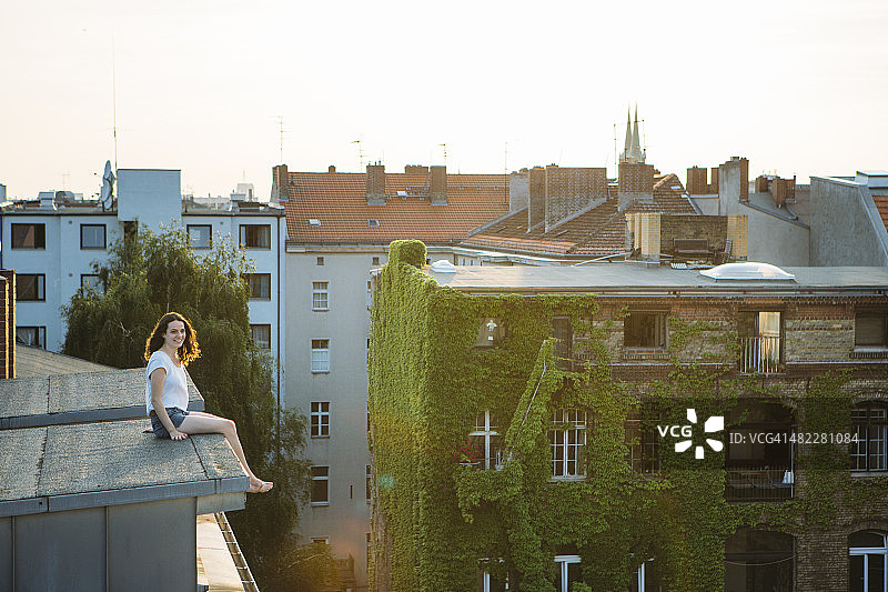无忧无虑的夏日:年轻女子勇敢地坐在屋顶上图片素材