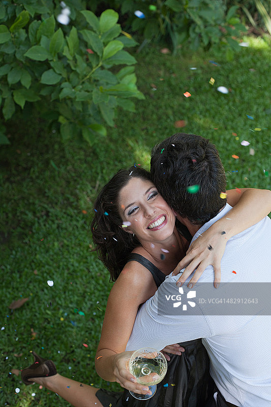 一对情侣在户外拥抱，白色的葡萄酒和五彩纸屑微笑着图片素材