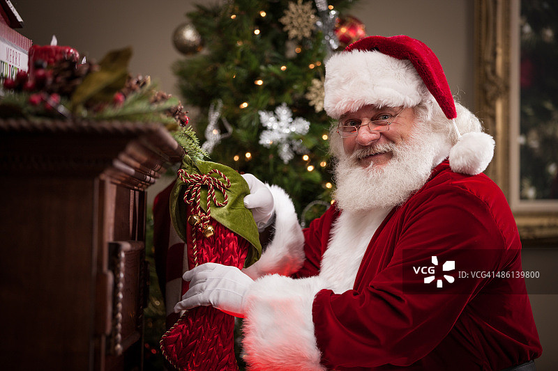 真正的圣诞老人把糖果放进长筒袜图片素材