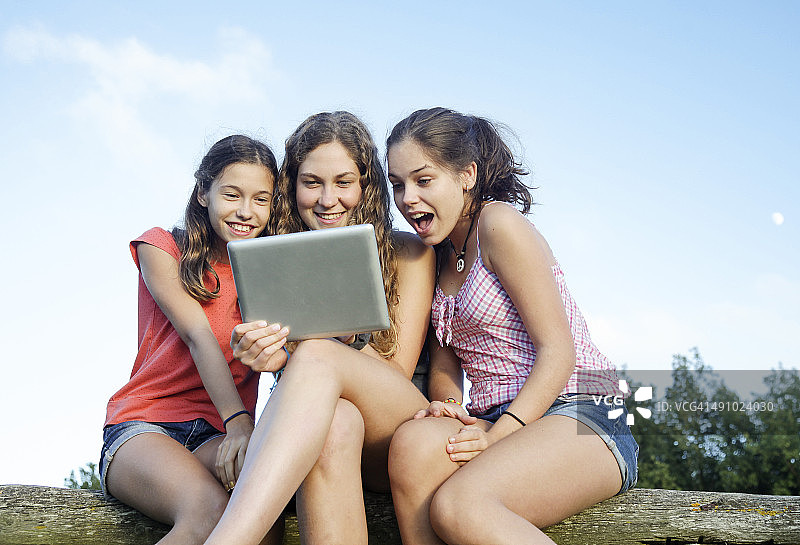 三个女孩，在户外看数字平板电脑图片素材