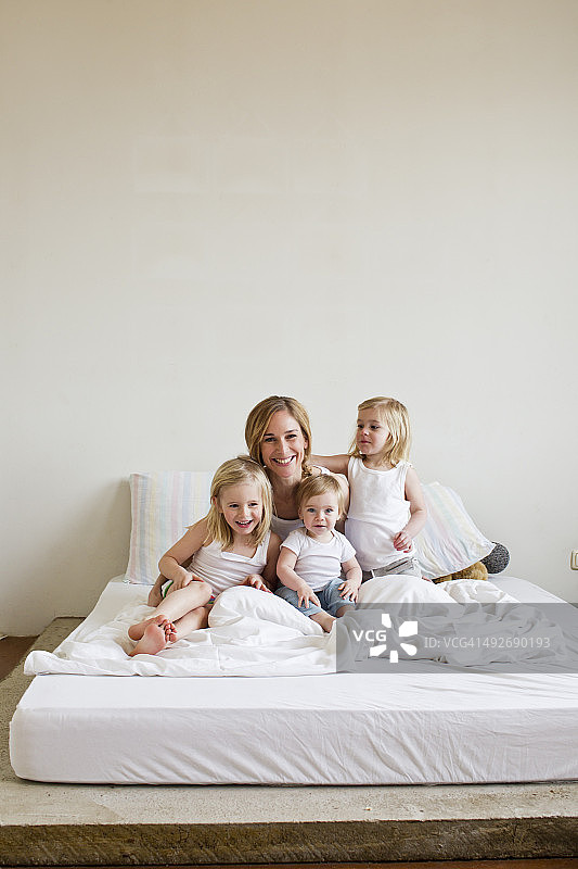 中年成年妇女的肖像在床上与三个女儿图片素材